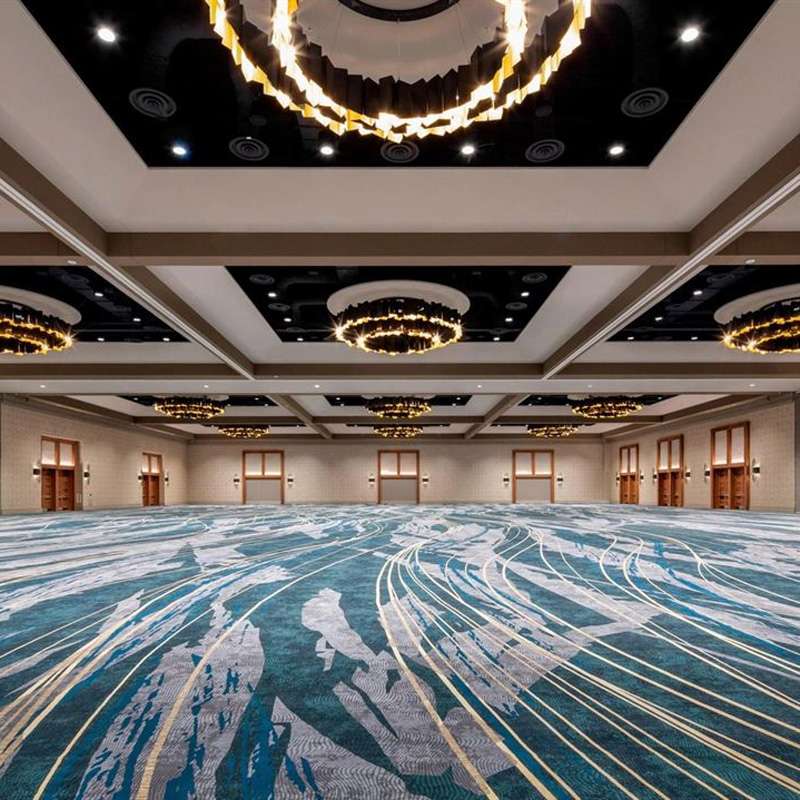 Spacious ballroom with blue carpet and chandeliers, perfect for events and gatherings in Denver, CO
