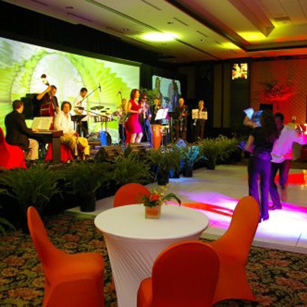 Large event room with tables, chairs, stage, and band setup by Spectrum Audio Visual in Denver, CO.