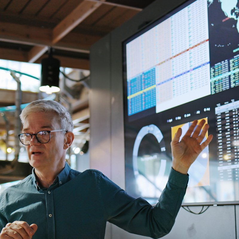 A man giving a speech with a screen behind him in Denver, CO