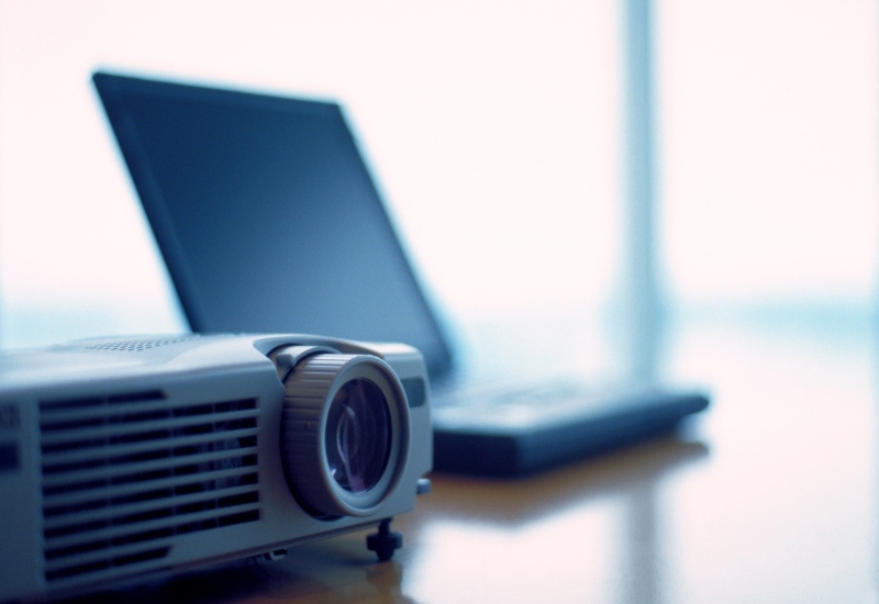 AV Equipment Sales in Denver, CO by Spectrum Audio Visual showing a projector & a laptop on a table