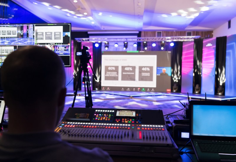 An event staging & production setup with operator, mixing board, & stage screen in Denver, CO